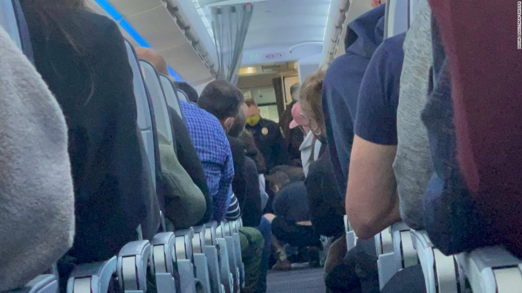 An American Airlines flight attendant hit a 'naughty passenger' in the head with a cup of coffee while trying to open the plane's exit door.