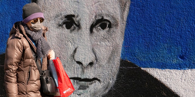 A woman walks past a mural depicting Russian President Vladimir Putin in Belgrade, Serbia, Saturday, March 12, 2022. 