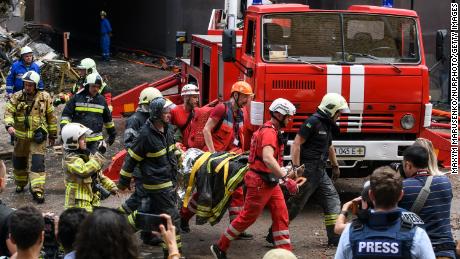 Rescue workers evacuate a person from an apartment building destroyed in a Russian air strike in the Shevchenkivsky district of Kyiv on June 26, 2022.