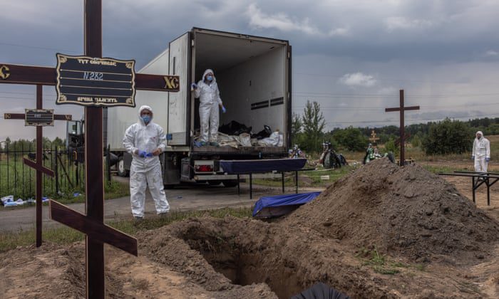 Workers place the remains of the dead in the coffins of unidentified people killed in Bucha district during a mass burial at a cemetery in Bucha, northwest of Kyiv, Ukraine.