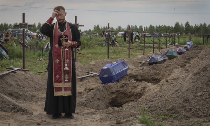 A priest prays for unidentified civilians killed by Russian forces in Bucha.