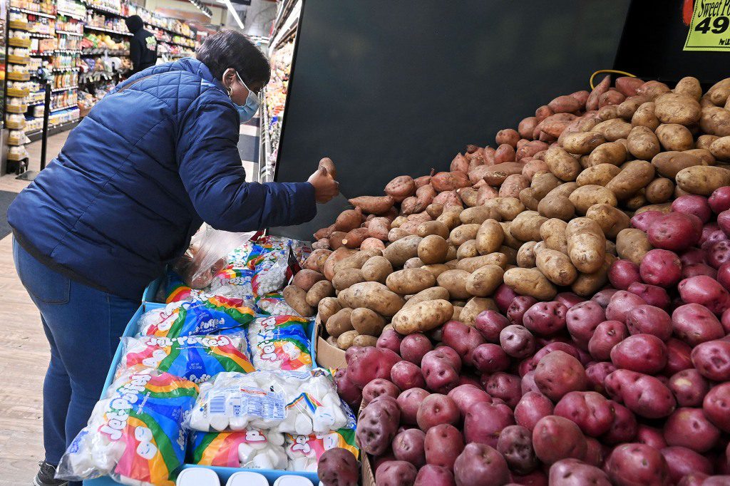 A woman distributes potatoes in a grocery store.