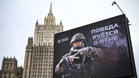 The Russian Foreign Ministry building is visible behind a billboard displaying the message 