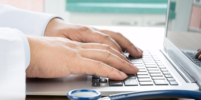Close-up of a doctor's hand typing on a computer